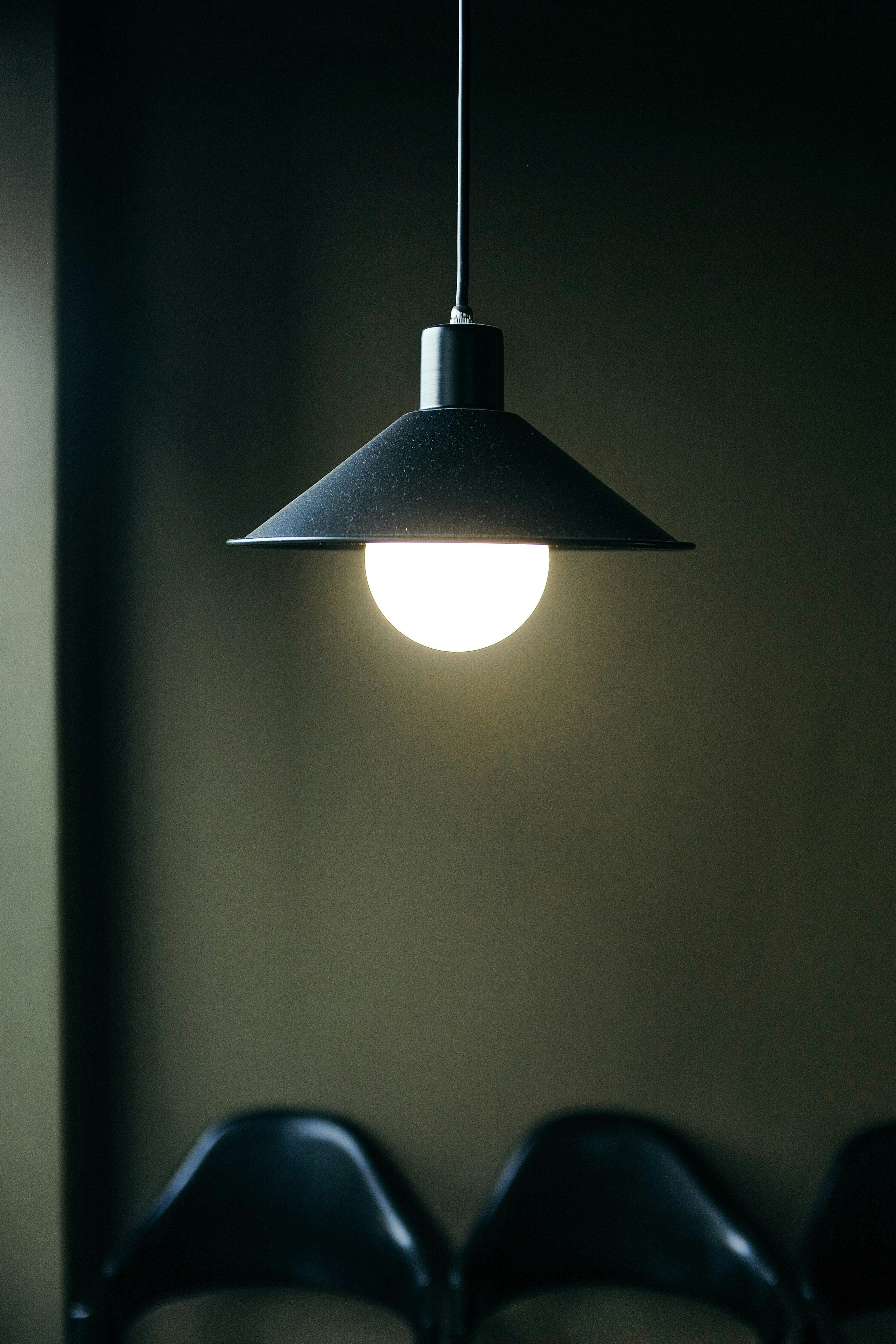 A pendant light glowing above a table in a dim room